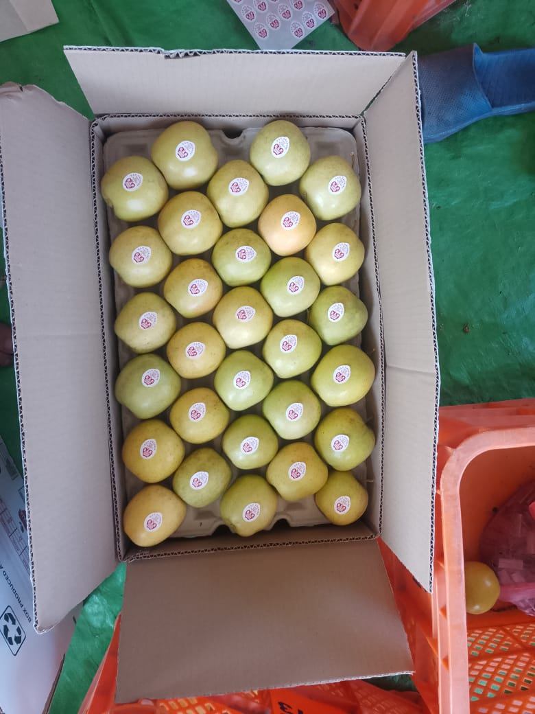 Open box of fresh golden apples with stickers